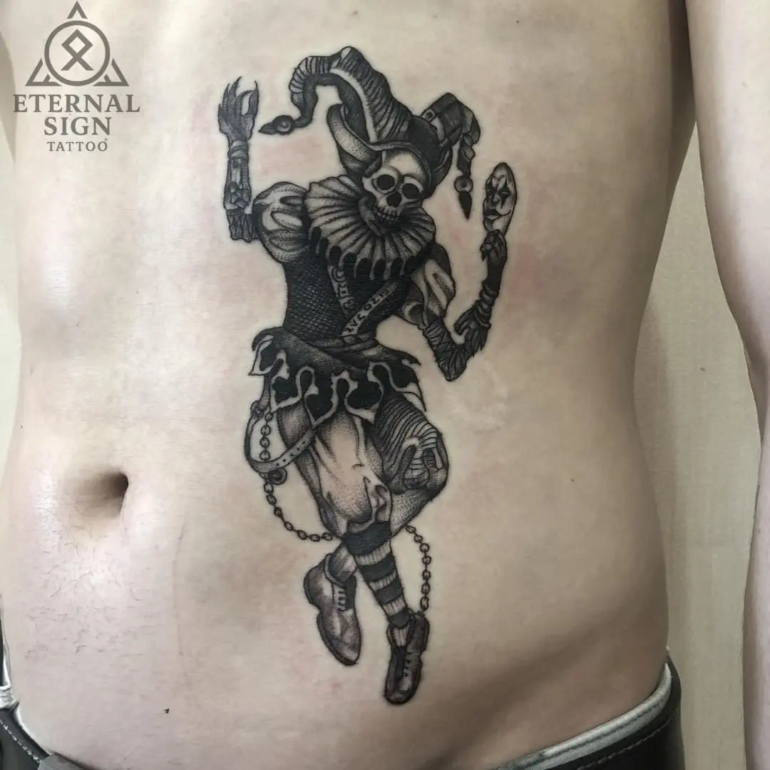 Detaljert blackwork-tatovering av en makaber narr med hodeskallehode på siden av magen i Fredrikstad.