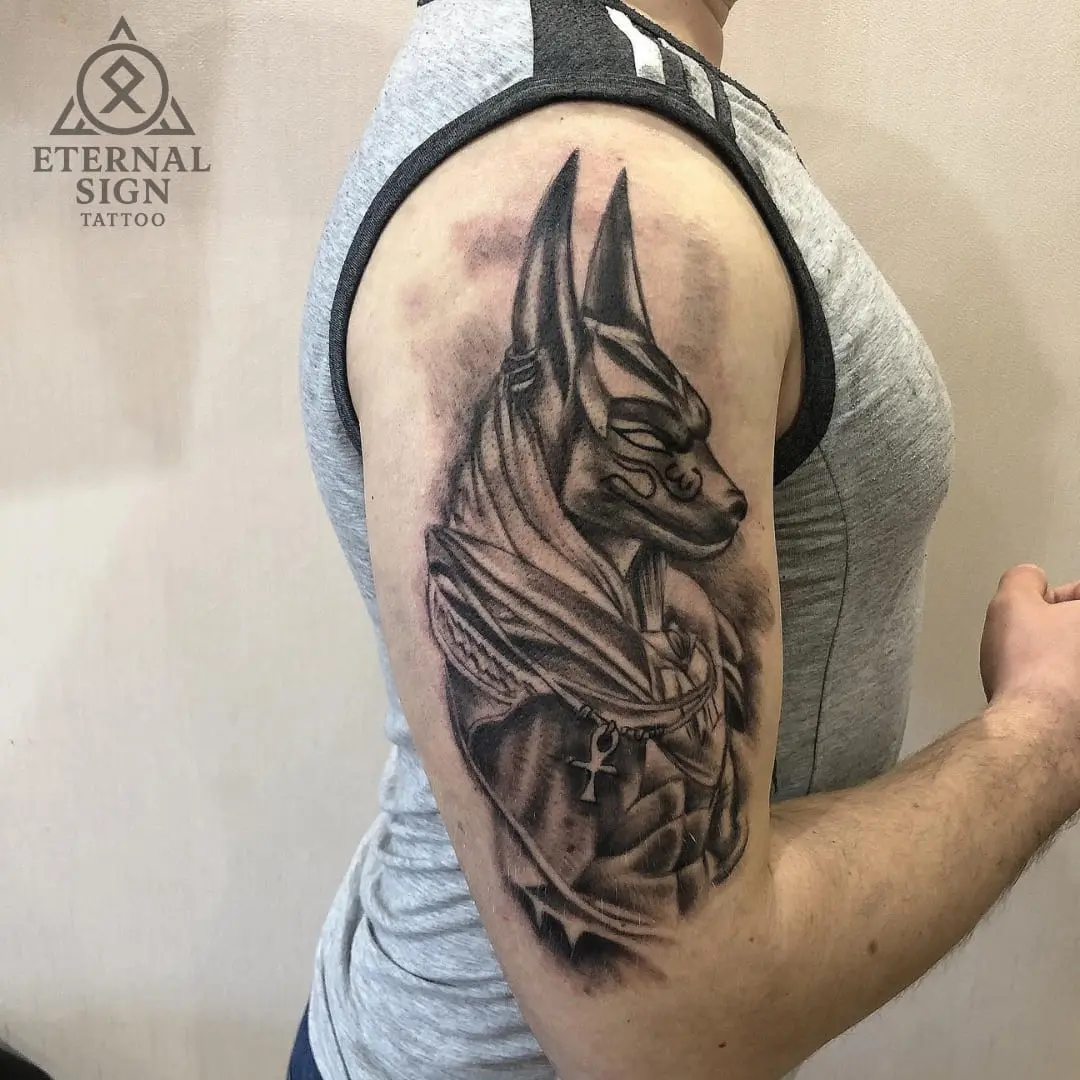 Portrett av den egyptiske guden Anubis på overarmen i black & grey med røykaktig bakgrunn.
