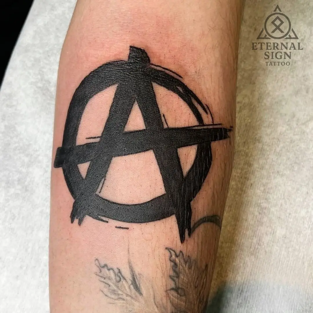 Grovt penselstrøk-symbol av anarki på leggen i grunge-stil i Fredrikstad.