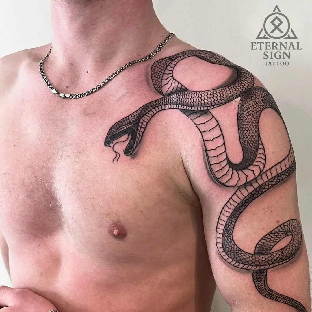 Stor detaljert black & grey slange, muligens kobra, som slynger seg fra bryst til skulder med intrikat skjellmønster.
