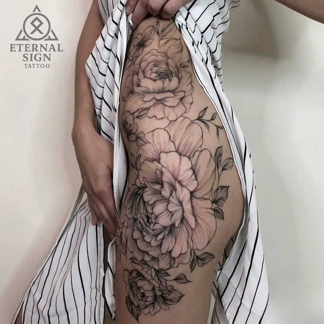 Blomstrende peoner med bladverk som dekker hofte og lår i blackwork-stil med dotwork-teknikk i Fredrikstad.