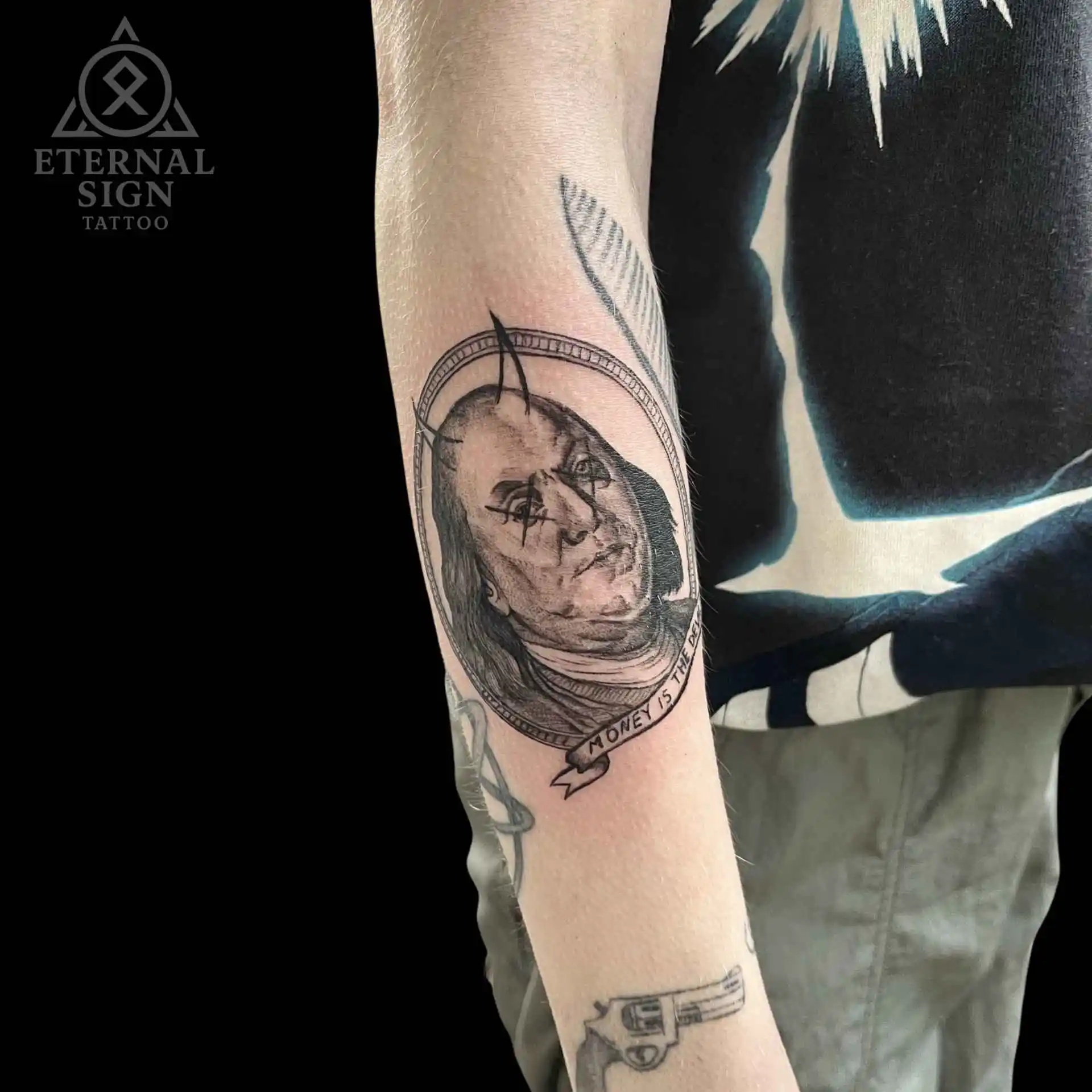 Detaljert black & grey tatovering av en demonisk Benjamin Franklin med horn og dryppende øyne, innrammet som et dollarportrett med banner 'Money is the Devil'.